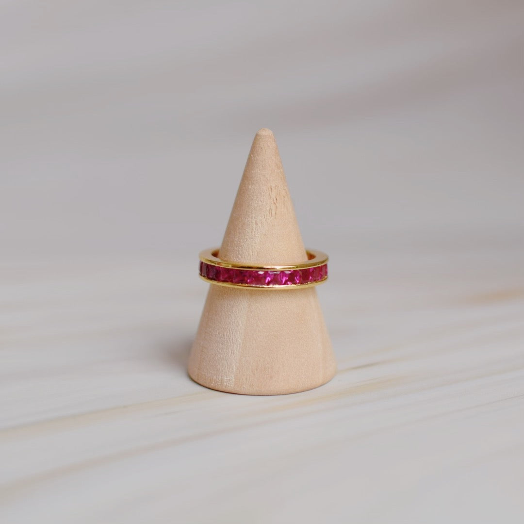 The Promise Ring Co. Ruby Channel set band diamond ring. With no prongs for a seamless look. Stacked or left alone to sparkle, this ring always looks beautiful. Shop in Ruby Simulant &amp; 18ct Gold.&nbsp;